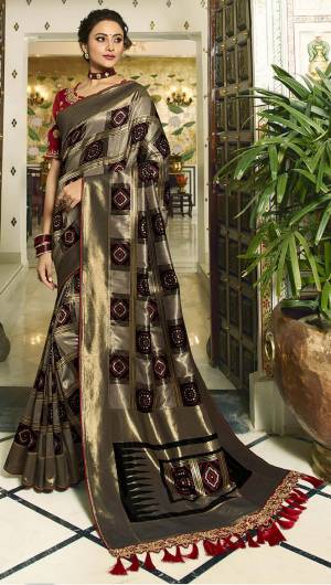 For A Proper Traditional Look, Grab This Designer Saree In Grey And Black Color Paired With Contrasting Red colored Blouse. This Heavy Weaved Saree Is Banarasi Art Silk Based Paired With Art Silk Fabricated Heavy Embroidered Blouse. Buy This Saree Now.