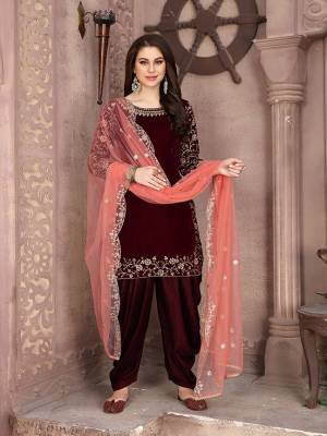 Grab This Beautiful Designer Patiala Suit In Maroon Color Paired With Contrasting Dark Peach Colored Dupatta. Its Embroidered Top Is Fabricated on Velvet Paired Santoon Bottom And Net Fabricated Dupatta. Buy Now.