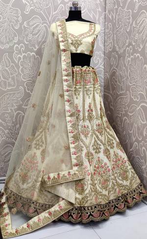 Get ready For The Upcoming Wedding Season With This Heavy Designer Lehenga Choli In Cream Color. This Pretty Heavy Embroidered And Attractive Lehenga Choli Is Fabricated on Satin Silk Paired With Net Fabricated Dupatta. Its Detailed Embroidery And Color Pallete Will earn You Lots Of Compliments From Onlookers. 