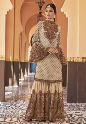 Adorn The Seasons Trend With This Trendy Designer Sharara Suit In Cream Color. Its Top Is Fabricated On Georgette Paired With Crepe Satin Bottom And Chiffon Fabricated Dupatta. This Lovely Suit Is Beautified With Detailed Attractive Prints And Stone Work. Buy This Lovely Piece Now.