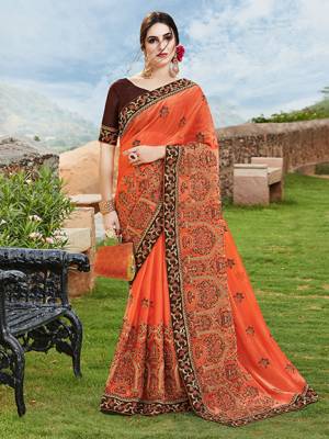 Get Ready For The Upcoming Wedding And Festive Season With This Designer Saree In Orange Color Paired With Contrasting Brown Colored Blouse. This Heavy Embroidered Saree Is Chiffon Silk Based Paired With Art Silk Fabricated Blouse. 