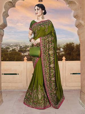 For A Royal Look, Grab This Heavy Designer Saree In Olive Green Color Paired With Olive Green Colored Blouse. This Saree And Blouse Are Silk Based Beautified With Heavy Embroidery. This Lovely Saree Is Suitable For Wedding And Party Wear. 