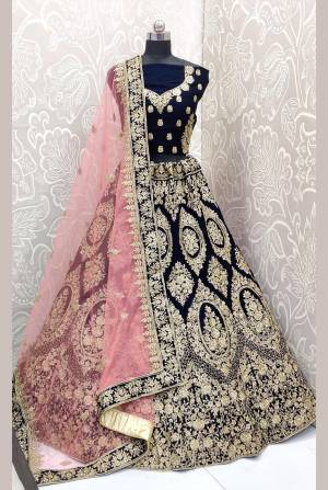 Be The Trendy Bride Wearing This Heavy designer Lehenga Choli In Navy Blue Color Paired With Contrasting Baby Pink Colored Dupatta. Its Blouse And Lehenga Are Fabricated On Velvet Paired With Net Fabricated Dupatta. Buy Now.