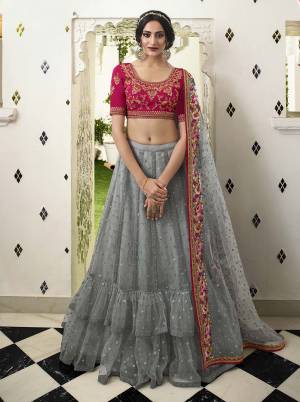 Add This Very Beautiful Designer Piece To Your Wardrobe With This Heavy Designer Lehenga Choli In Dark Pink Colored Blouse Paired With Grey Colored Lehenga And Dupatta, Its Pretty Embroidered Blouse Is Chinon Based Paired With Net Fabricated Lehenga And Dupatta. 