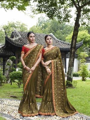 Celebrate This Festive And Wedding Season Wearing This Heavy Designer Saree In Olive Green Color Paired With Red Colored Blouse. This Pretty Saree And Blouse Are Silk Based Beautified With Heavy Embroidery Work. 