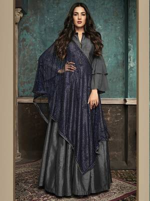 Enhance Your Personality Wearing This Designer Floor Length Suit In Dark Grey Color Paired With Contrasting Navy Blue Colored Heavy Dupatta. Its Elegant Floor Length Top Is Fabricated On Art Silk Paired With Santoon Bottom And Net Fabricated Dupatta Beautified With Heavy Stone Work. 