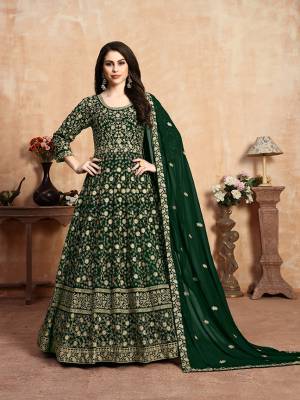 Get Ready For The Upcoming Wedding Season With This Heavy Designer Floor Length Suit In Dark Green Color. Its Heavy Embroidered Top Is Fabricated On Georgette Paired With Santoon Bottom And Georgette Fabricated Dupatta Which Has Pretty Elegant Embroidered Buttis And Lace Border. 