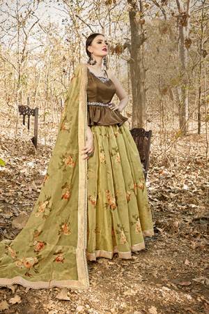 Here Is A Tendy Designer Lehenga Choli In Peplum Pattern With Brown Colored Blouse Paired With Contrasting Olive Green Colored Lehenga And Dupatta. Its Blouse Is Fabricated On Art Silk Paired With Orgenza Based Lehenga And Dupatta. Buy This Trendy Piece Now.