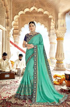 Get Ready For The Upcoming Wedding Season With This Designer Saree In Turquoise Blue Color Paired With Contrasting Navy Blue Colored Blouse. This Saree Is Fabricated On Satin Georgette Paired With Art Silk Fabricated Blouse. 