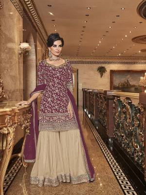 Bold And Elegant Color Pallete IS Here With This Designer Sharara Suit In Wine Colored Top And Dupatta Paired With Contrasting Beige Colored Bottom. Its Top, Bottom And Dupatta Are Fabricated On Net Beautified With Heavy Embroidery. Buy Now.
