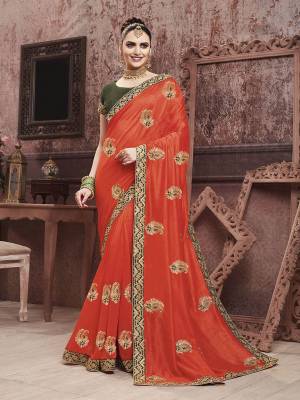 Celebrate This Festive Season With Beauty And Comfort In This Motif Embroidered Yet Elegant Saree In Orange Color Paired With Contrasting Dark Green Colored Blouse. This Saree And Blouse are Silk Based Which Gives A Rich Look To Your Personality. 