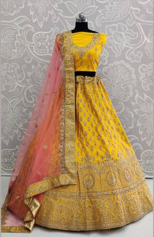 Look Pretty In This Very Beautiful And Heavy Designer Lehenga Choli In Yellow Color Paired With Contrasting Baby Pink Colored Dupatta. Its Heavy Embroidered Blouse And Lehenga Are Fabricated On Satin Silk Paired With Net Fabricated Dupatta. Buy Now