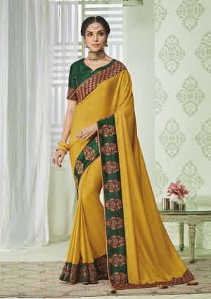 Enhance Your Personality Wearing This Rich Silk Based Designer Saree In Yellow color Paired With Contrasting Dark Green Colored Blouse. It Is Beautified With Pretty Embroidery Over The Lace Border. 