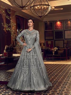 Add This Lovely Shade To Your Wardrobe With This Heavy Designer Floor Length Suit In Grey Color. Its Heavy Embroidered Top Is Fabricated On Net Paired With Soft Silk Bottom And Net Dupatta. 