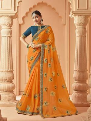 Add This Very Pretty And Elegant Looking Designer Saree In Light Orange Color Paired With Contrasting Teal Blue Colored Blouse. This Saree Is Fabricated On Georgette Beautified With Pretty Embroidered Motifs Paired With Art Silk Fabricated Blouse. 