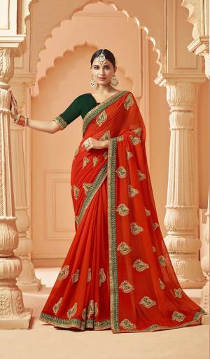 Add This Very Pretty And Elegant Looking Designer Saree In Orange Color Paired With Contrasting Dark Green Colored Blouse. This Saree Is Fabricated On Georgette Beautified With Pretty Embroidered Motifs Paired With Art Silk Fabricated Blouse. 