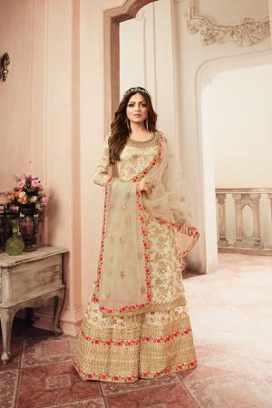 Look Pretty In This Lovely Heavy Designer Sharara Suit In Cream Color. Its Top Is Jacquard Silk Based Paired With Embroidered Net Fabricated Bottom And Dupatta. Buy Now. 