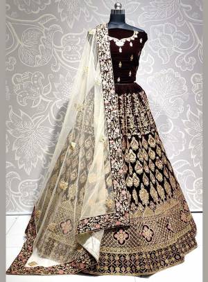 Get Ready For The Upcoming Wedding Season With This Heavy Designer Lehenga Choli In Brown Color Paired With Off-White Colored dupatta. This Lehenga Choli Is Fabricated On Velvet Paired With Net Fabricated Dupatta. 