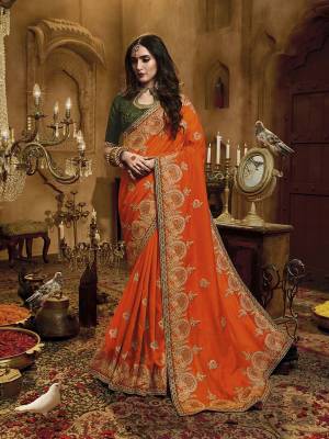 Get Ready For The Upcoming Wedding Season With Heavy Designer Saree In Orange Color Paired With Contrasting Green Colored Blouse. This Saree Is Fabricated On Satin Silk Paired With Art Silk Fabricated Blouse. It Is Beautified With Heayv Detailed Embroidery Giving An Attractive Look. 