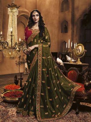 You Will Definitely Earn Lots Of Compliments Wearing This Heavy Embroidered Designer Saree In Olive Green Color Paired With Red Colored Blouse. This Pretty Saree Is Satin Silk Based Paired With Art Silk Fabricated Blouse. 