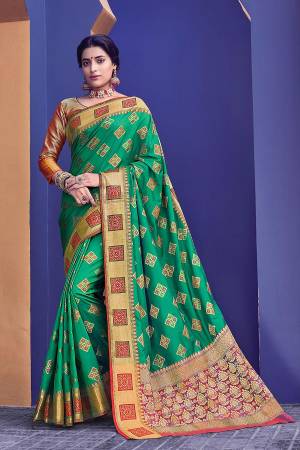 This Festive Season, Adorn A Proper Traditional Look Wearing This Saree In Green Color Paired With Orange Colored Blouse. This Saree And Blouse Are Fabricated On Banarasi Silk Beautified With Weave All Over. 