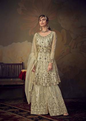 Grab This Very Beautiful Heavy Designer Sharara Suit In Cream Color. Its Pretty Embroidered Top, Bottom And Dupatta Are Fabricated On Net Beautified With Tone To Tone Embroidery Giving A Heavy Yet Subtle Look. Its Top Is Semi-Stitched With Fully Stitched Sharara. 