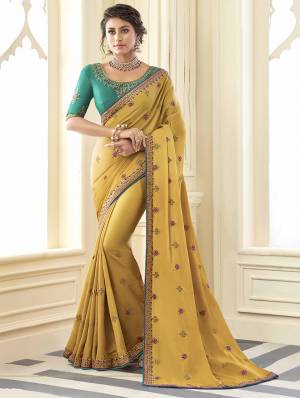 Get Ready For The Upcoming Wedding And Festive Season Wearing This Attractive Looking Designer Saree In Musturd Yellow Color Paired With Contrasting Turquoise Blue Colored Blouse. This Saree Is Fabricated On Satin Silk Paired With Art Silk Fabricated Blouse. This Pretty Saree And Blouse Are Beautified With Attractive Detailed Embroidery. 