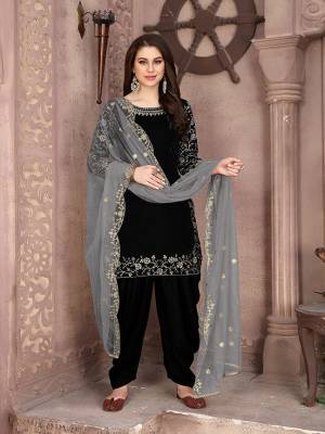 Here Is A Very Pretty Designer Suit In Black Color Paired With Paired With Grey Colored Dupatta. Its Embroidered Top Is Fabricated On Velvet Paired With Santoon Bottom And Net Fabricated Dupatta. This Pretty Suit Is Light In Weight And Easy To Carry All Day Long. 